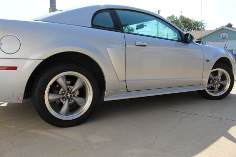 2002 Ford Mustang - Side view of a silver coupe with tinted windows and five-spoke wheels.