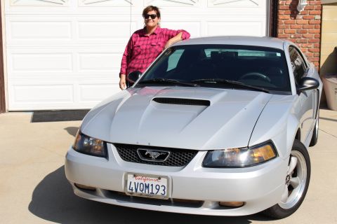 2002 Ford Mustang - A silver 2002 Ford Mustang is parked in front of a garage door, with a person leaning on the car.
