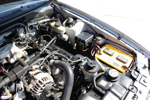 2002 Ford Mustang - The engine bay of a 2002 Ford Mustang is visible, with components like the battery and alternator clearly depicted.