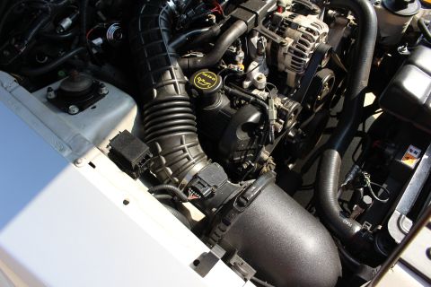 2002 Ford Mustang - Close-up of the engine bay in a 2002 Ford Mustang, showing the air intake system and alternator.