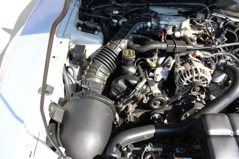 2002 Ford Mustang - The engine bay of a white 2002 Ford Mustang, the air intake system and alternator.