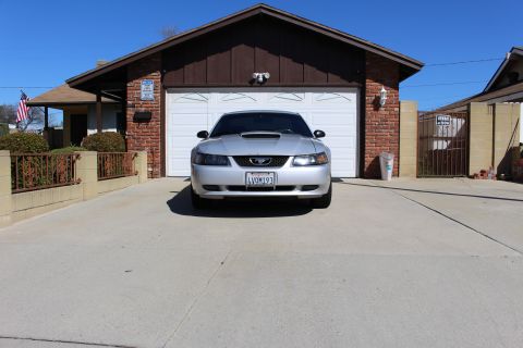2002 Ford Mustang - Front view of a silver 2002 Ford Mustang parked in a driveway with a garage in the background.