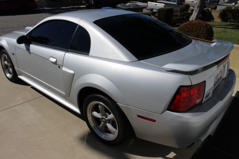 2002 Ford Mustang - Silver 2002 Ford Mustang coupe with tinted windows and a rear spoiler is parked on a driveway.