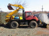 1990 Ford Bronco - A red and yellow backhoe loader is parked outdoors on a sunny day.
