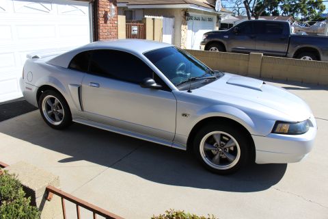 2002 Ford Mustang - A silver 2002 Ford Mustang GT is parked in a driveway with a pickup truck in the background.