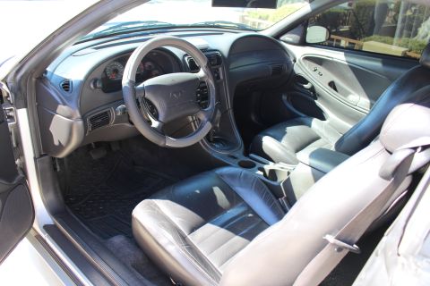 2002 Ford Mustang - The interior of a Ford Mustang shows black leather seats and a dashboard with a prominent steering wheel.