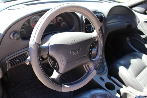 2002 Ford Mustang - The interior of a 2002 Ford Mustang is visible, the steering wheel, instrument cluster, and seats.