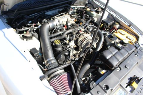 2002 Ford Mustang - Engine bay of a white 2002 Ford Mustang, showing an aftermarket intake system and air filter.