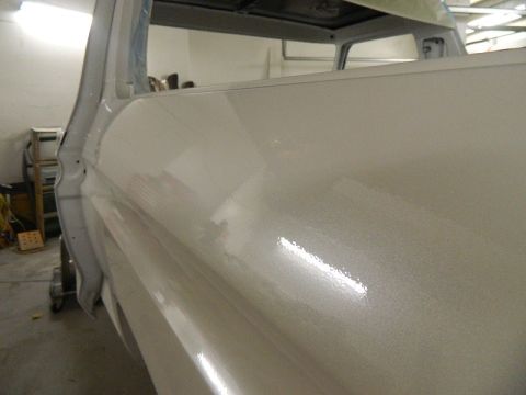 1979 Ford Bronco - A white vehicle's side panel is shown, reflecting light from overhead fixtures.