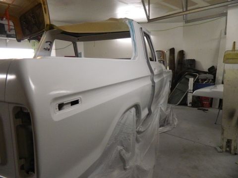 1979 Ford Bronco - The body of a Ford Bronco is being prepped for paint in a garage setting, with parts of the interior and exterior covered.