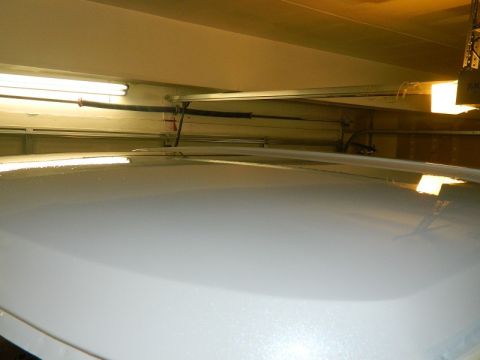 1979 Ford Bronco - The top of a white vehicle is shown in a garage setting, with the overhead door tracks and springs in view.