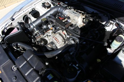 2002 Ford Mustang - Close-up view of a car's engine bay, showing various mechanical parts and an aftermarket air intake system.