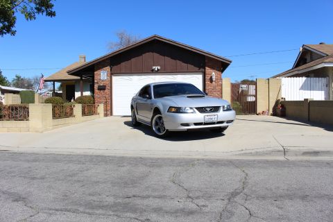 2002 Ford Mustang - A silver 2002 Ford Mustang is parked in front of a suburban home's garage.