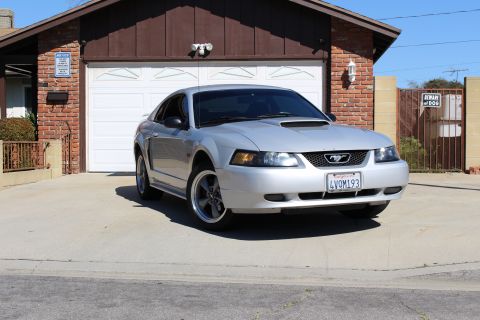 2002 Ford Mustang - Silver 2002 Ford Mustang parked in a driveway in front of a garage.