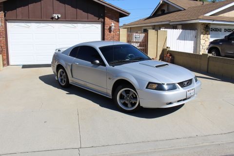 2002 Ford Mustang - A silver 2002 Ford Mustang is parked in a residential driveway in front of a garage.