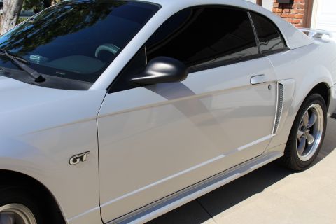 2002 Ford Mustang - A silver 2002 Ford Mustang GT is parked outside, showing its side profile and GT badging.