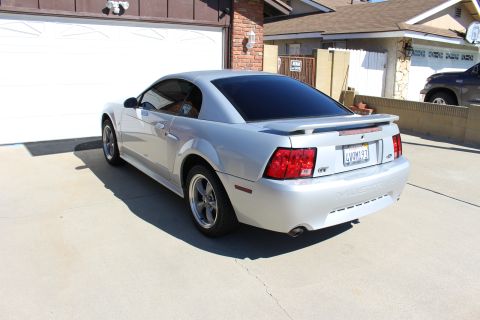 2002 Ford Mustang - A silver 2002 Ford Mustang GT is parked in a driveway with a garage in the background.