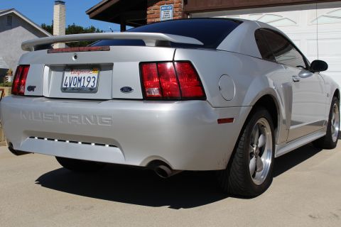 2002 Ford Mustang - Rear view of a silver 2002 Ford Mustang GT with a spoiler and custom wheels.