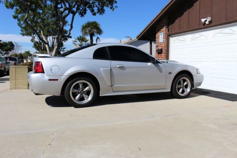 2002 Ford Mustang - A silver 2002 Ford Mustang is parked on a driveway in front of a garage on a sunny day.