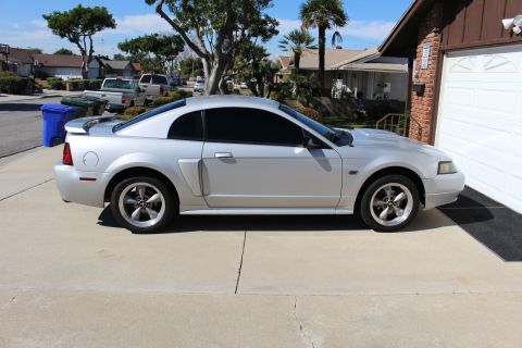 2002 Ford Mustang - A silver 2002 Ford Mustang is parked in a suburban driveway next to a garage.