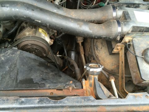 1989 Ford Bronco - Close-up view of engine components including hoses and the AC compressor.