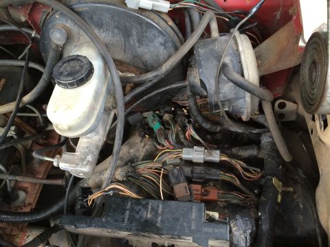 1989 Ford Bronco - Close-up view of the engine bay wiring harness and brake fluid reservoir.