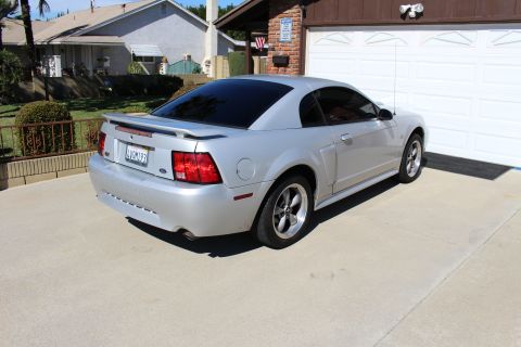 2002 Ford Mustang - Silver 2002 Ford Mustang with tinted windows parked in front of a garage.