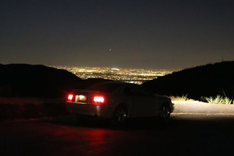 2002 Ford Mustang - A 2002 Ford Mustang is parked on a hill overlooking a city at night.