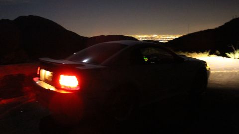 2002 Ford Mustang - A 2002 Ford Mustang is parked on a hillside overlooking a city at night.