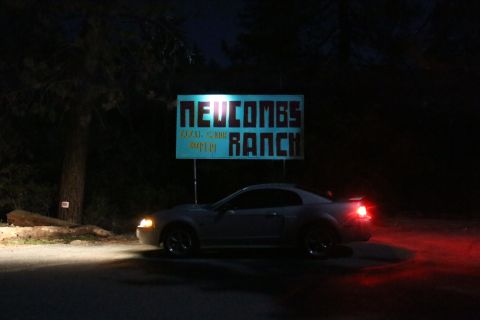 2002 Ford Mustang - A silver Ford Mustang is parked at night near a lit sign for Newcombs Ranch.