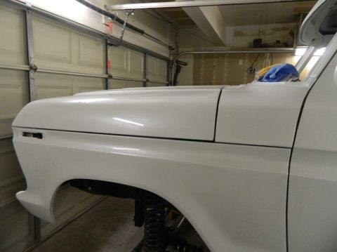 1979 Ford Bronco - Front fender and hood of a white 1979 Ford Bronco, possibly undergoing restoration.
