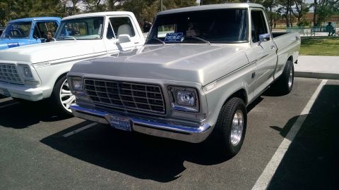 1979 Ford Bronco - A silver 1979 Ford Bronco is parked in a lot with other trucks. The license plate is visible.