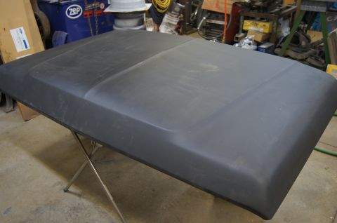 1979 Ford Bronco - A black hood rests on a metal stand in a cluttered workshop environment.