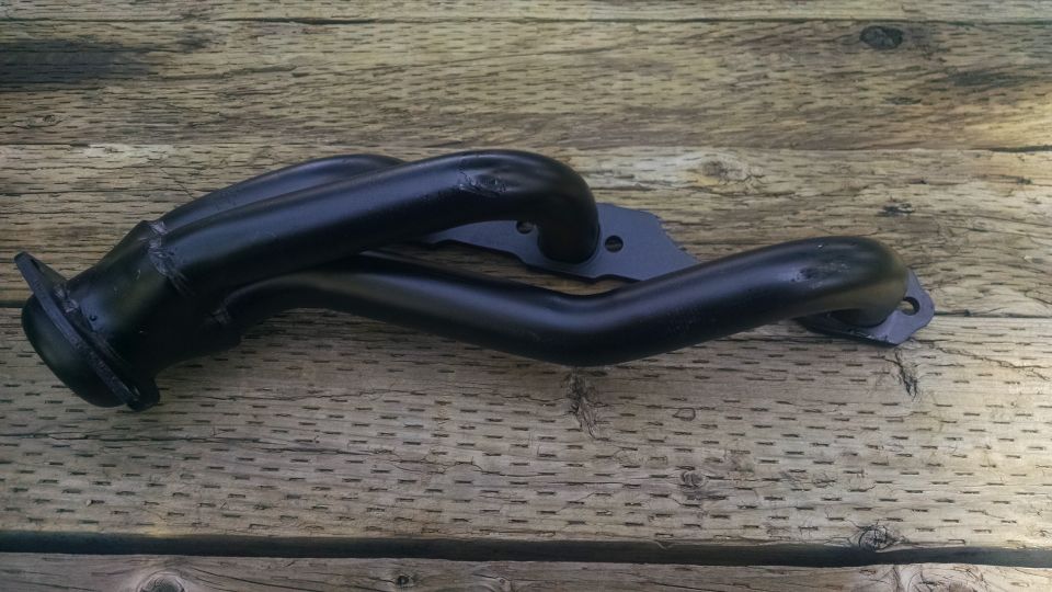 Black exhaust manifold on wooden planks