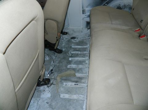 1979 Ford Bronco - The floor of a vehicle interior is exposed, revealing a concrete surface and remnants of removed flooring material.