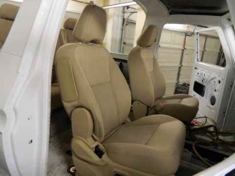 1979 Ford Bronco - Interior view of a vehicle with tan cloth seats and a white door panel, showing exposed wiring.