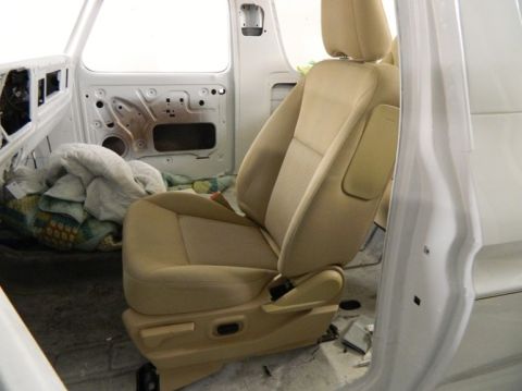 1979 Ford Bronco - Interior view of a vehicle with a tan cloth seat and exposed door mechanisms.
