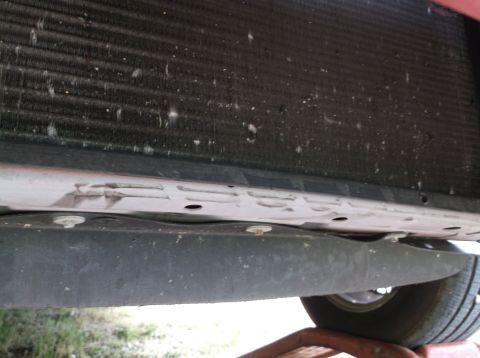 1999 Mercury Grand Marquis - Undercarriage view shows the radiator and a plastic shield, with a tire visible on the right side.