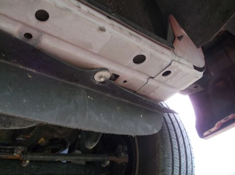 1999 Mercury Grand Marquis - Underside view of a car's front bumper, splash guard, and tire, revealing structural components.