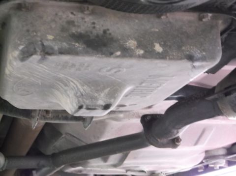 1999 Mercury Grand Marquis - The underside of a vehicle shows the oil pan and exhaust system, with some text visible on the pan.