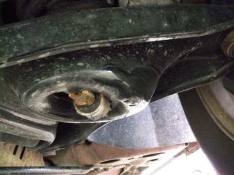 1999 Mercury Grand Marquis - Undercarriage view of a vehicle's suspension system, showing a rusty bolt and part of a tire.