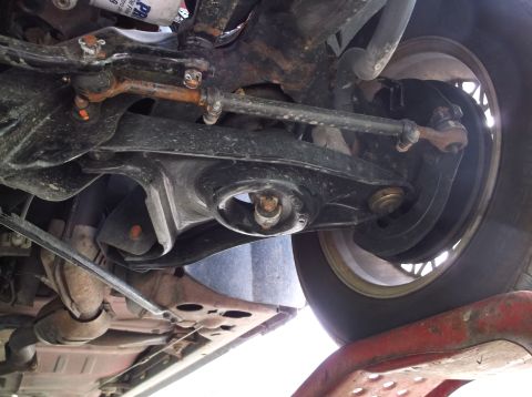 1999 Mercury Grand Marquis - Close-up of vehicle suspension components, including tie rods and control arms, with a tire visible.