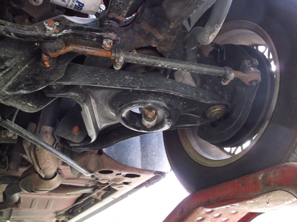 Underside view of car suspension parts and tire. Supermotors.net logo visible
