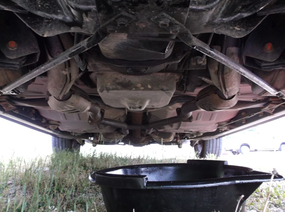 car's undercarriage with oil drain pan below
