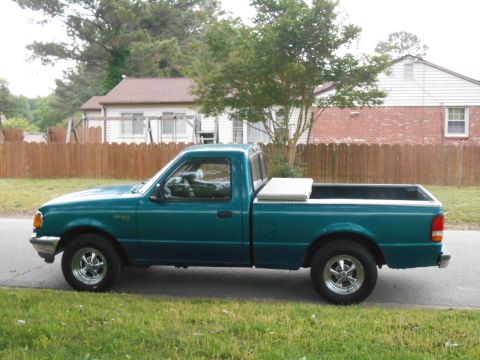 1997 Ford Ranger - A teal pickup truck is parked on the side of the road with a residential house in the background.