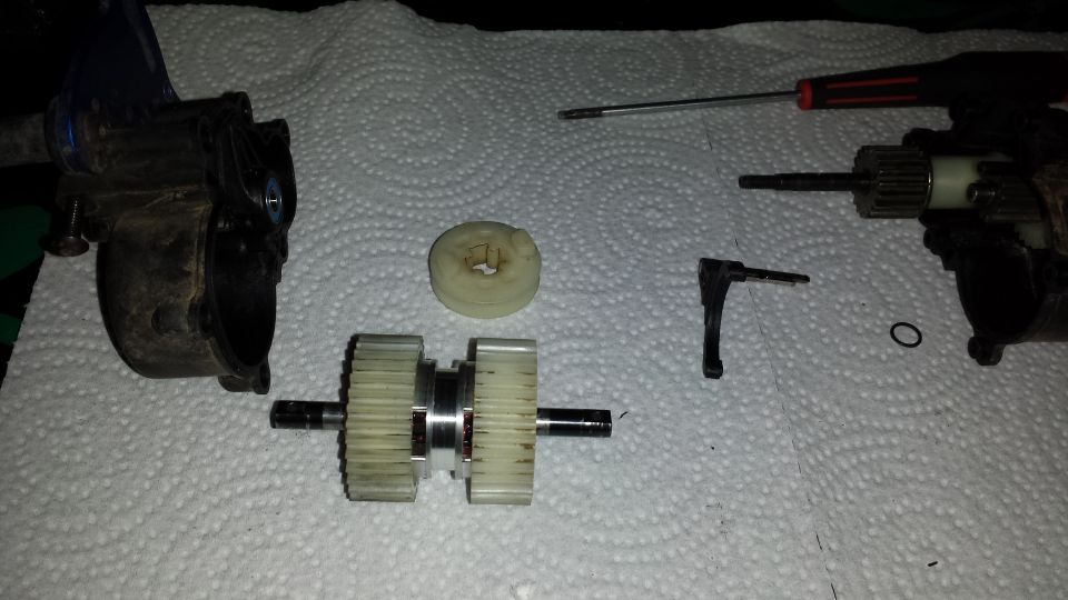 RC car gearbox and differential parts laid out on paper towels. Includes gears, shafts, and housing