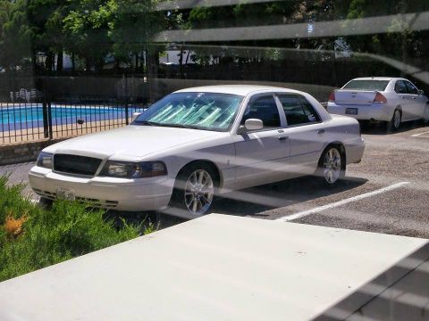 2000 Mercury Grand Marquis - A white sedan is parked in a lot near a swimming pool, with another car visible in the background.