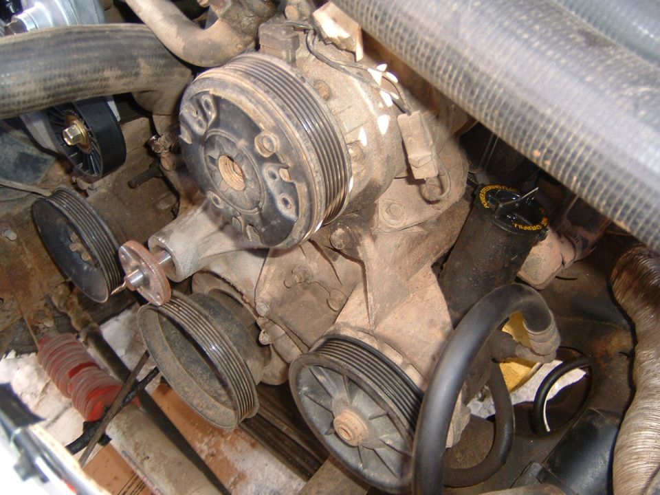Engine water pump and pulleys with visible text on reservoir cap