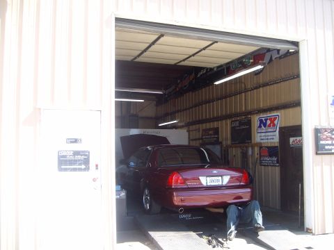 2004 Ford Crown Victoria - A maroon Ford Crown Victoria is on a dynamometer with a mechanic underneath.