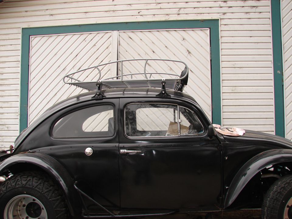 Black VW Beetle with roof rack parked in front of a garage door